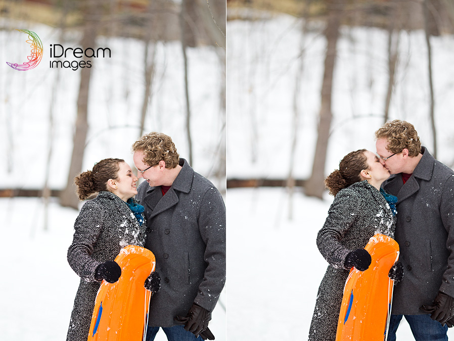 couple kissing in the snow holding a sled